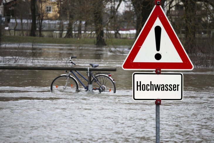 symbolic picture, bicycle is under water because of high water, sign warns of high water